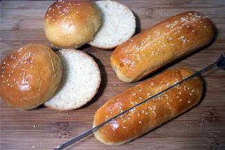 开始制作汉堡包和热狗。先用等分器从汉堡包坯底部切开，高度约1~1.5厘米处。热狗坯从中间切开，但是不要切断。