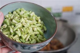 再将豇豆改刀下锅同炒至出味。