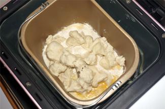 将黄油除外的主面团食材（主面团：高筋粉80克 牛奶33克 细砂糖27克 盐4克 全蛋液27克 炼奶40克 黄油21克 酵母1克）按照先液体后固体的顺序放入面包机里，然后将发酵好的中种面团撕成小块，放入面包桶里，启动揉面程序，时间20分钟。