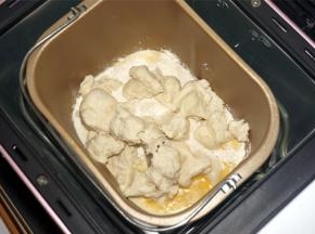 将黄油除外的主面团食材（主面团：高筋粉80克 牛奶33克 细砂糖27克 盐4克 全蛋液27克 炼奶40克 黄油21克 酵母1克）按照先液体后固体的顺序放入面包机里，然后将发酵好的中种面团撕成小块，放入面包桶里，启动揉面程序，时间20分钟。