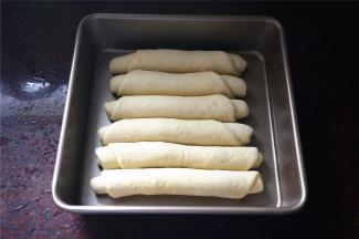 排放入8寸的方形不粘蛋糕盘中，盖上保鲜膜，放入烤箱，启动发酵程序进行二次发酵，时间约40分钟。