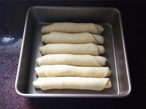 排放入8寸的方形不粘蛋糕盘中，盖上保鲜膜，放入烤箱，启动发酵程序进行二次发酵，时间约40分钟。