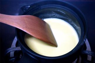 将奶锅里的一半量的牛奶倒入到蛋黄中，用打蛋器稍微拌均匀后倒回到奶锅中，转为小火，并用木铲不停搅拌，熬至法式浓汤般的浓稠度后就可以熄火了。