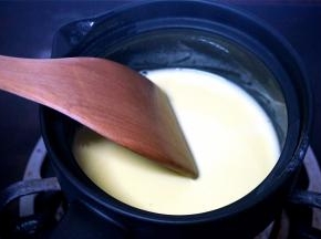 将奶锅里的一半量的牛奶倒入到蛋黄中，用打蛋器稍微拌均匀后倒回到奶锅中，转为小火，并用木铲不停搅拌，熬至法式浓汤般的浓稠度后就可以熄火了。