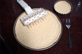 发酵好的面团，排气，松弛15分钟后擀成圆形薄片，放入披萨盘中，并戳上小孔，防止烤的时候鼓起。（这个面团的量是1个8寸的量，我这次做的是薄皮披萨，用的是9寸+4寸披萨盘。）