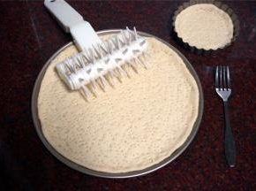 发酵好的面团，排气，松弛15分钟后擀成圆形薄片，放入披萨盘中，并戳上小孔，防止烤的时候鼓起。（这个面团的量是1个8寸的量，我这次做的是薄皮披萨，用的是9寸+4寸披萨盘。）