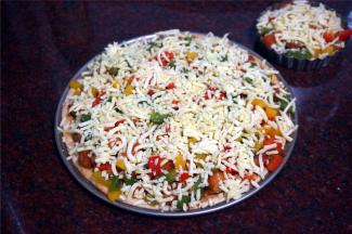 然后铺上炒熟的鸡腿肉和彩椒，表面再铺上剩余的马苏里拉芝士。放入预热好的烤箱中层，上下火210度，烤15分钟。