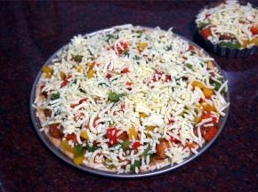 然后铺上炒熟的鸡腿肉和彩椒，表面再铺上剩余的马苏里拉芝士。放入预热好的烤箱中层，上下火210度，烤15分钟。