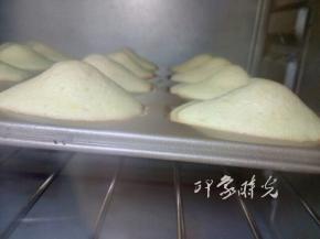 将模具放入预热好的烤箱，上下火190度，烤13-15分钟。图中是烤到8分钟的时候，此时玛德琳背面已经鼓起来了，并且边缘有一点发焦了。玛德琳的贝壳模具，四周薄，中间厚，在烤的时候，四周很容易成熟定型，而中间则会继续膨胀，就会鼓出高高的肚子。