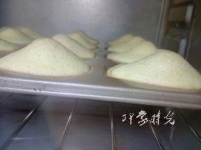 将模具放入预热好的烤箱，上下火190度，烤13-15分钟。图中是烤到8分钟的时候，此时玛德琳背面已经鼓起来了，并且边缘有一点发焦了。玛德琳的贝壳模具，四周薄，中间厚，在烤的时候，四周很容易成熟定型，而中间则会继续膨胀，就会鼓出高高的肚子。