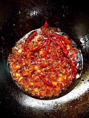 香味出来后，放2勺豆瓣酱、1勺干花椒和适量干辣椒，慢慢炒出红油来。注意一定要用小火慢慢炒，红油才炒得亮。