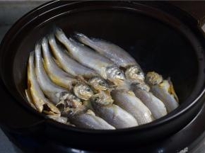 再加入少许玉米油加热，再将洗净控水的小黄鱼摆放在锅里。