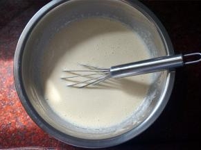 将烧开的牛奶分次倒入到蛋糕糊中，边倒入边搅拌，然后放置一旁冷却。