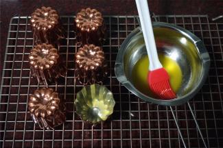 烤箱上下火230度预热。铜制模具刷上一层黄油，然后将模具倒扣，流出多余的黄油。