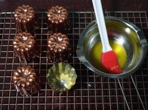 烤箱上下火230度预热。铜制模具刷上一层黄油，然后将模具倒扣，流出多余的黄油。