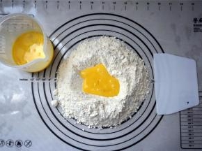 富强粉，泡打粉混合过筛到揉面垫上，然后中间挖空，倒入全蛋液。揉成湿润的面团，非常粘软的状态，据说这样做出来的沙琪玛才松软。