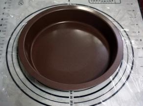 在面团上方铺上一片保鲜膜，然后用派盘中心按压面团至扁。