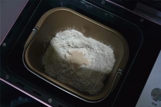 将除黄油外的面团食材放入面包机中，启动揉面程序，时间20分钟。