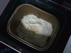 将除黄油外的面团食材放入面包机中，启动揉面程序，时间20分钟。