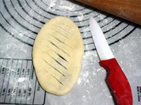 将其擀开成长舌状，然后用刀在表层面皮上斜着划口。