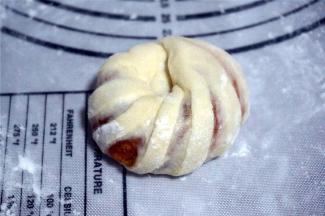 翻面后将面团自上而下卷起来，两头搓尖后交叉叠在一起。