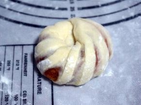 翻面后将面团自上而下卷起来，两头搓尖后交叉叠在一起。