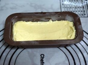 将面糊分次从顶端倒入，轻敲模具，震出面糊中的空气，并用橡皮刮刀抹平表面，呈弓形向内凹。