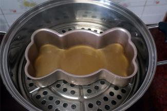 水沸腾后，将模具放入蒸锅里，然后倒一层黄糖粉浆，盖上锅盖，蒸5分钟。