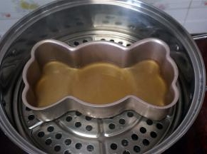 水沸腾后，将模具放入蒸锅里，然后倒一层黄糖粉浆，盖上锅盖，蒸5分钟。
