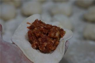 醒发好的面团，先分成大小相等的小剂子，再擀成面皮，半调配好的馅料包在面皮里。