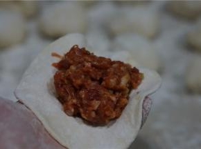 醒发好的面团，先分成大小相等的小剂子，再擀成面皮，半调配好的馅料包在面皮里。