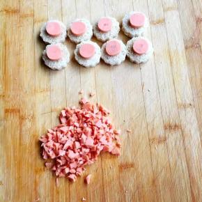 3、	火腿肠切成八个小圆片，放在花片上，剩下的切碎