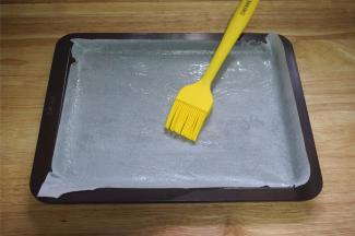 学厨的棕色长方形饼干盘，铺上油纸，并刷上一层油。