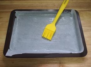 学厨的棕色长方形饼干盘，铺上油纸，并刷上一层油。