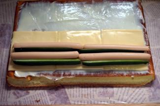 蛋糕出炉后马上倒扣脱模，撕去底部的吸油纸，然后盖上冷却到温温的状态时抹上色拉酱，然后铺上3片芝士片，摆上青瓜条和火腿肠。