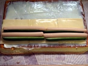 蛋糕出炉后马上倒扣脱模，撕去底部的吸油纸，然后盖上冷却到温温的状态时抹上色拉酱，然后铺上3片芝士片，摆上青瓜条和火腿肠。