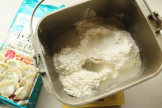 面粉放入面包机内筒，加入水和盐。