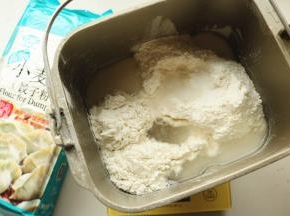 面粉放入面包机内筒，加入水和盐。