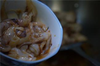 五花肉煎炒的熟透后再将腌制好的鱿鱼下锅。