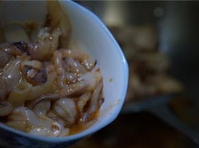 五花肉煎炒的熟透后再将腌制好的鱿鱼下锅。