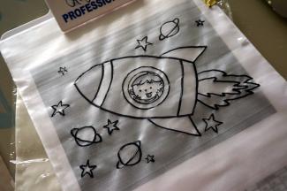 图案纸上放上透明的转印片，然后表面再放上一张糯米纸，用可食用色笔描绘图案。