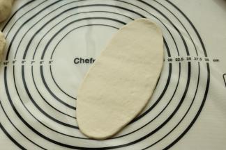 取一个面团揉圆，擀开成牛舌状。