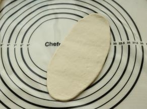 取一个面团揉圆，擀开成牛舌状。