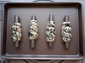 从粗的一端开始卷起，收口朝下，表面刷上清水，撒上黑芝麻。