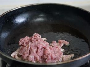 一边制做面条，一边炒制辅炒，锅里加油将肉丝下锅煎炒。