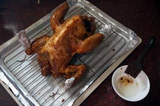 烤盘垫上锡纸，放入一个13寸不粘冷却架，将腌制好的光鸡胸部朝上放在网架上， 鸡翅尖和腿尖用锡纸包裹。烘烤前，给全鸡刷上一层食用油，锁住酱汁。