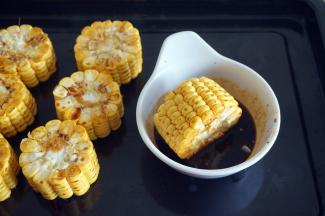 在烤鸡的过程中，将玉米切段，分别在腌鸡的酱料上打滚一圈。