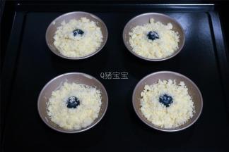 剩余的面糊，平均分配到4个蛋挞模具中，同样放上一颗蓝莓，撒上酥粒。