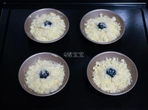 剩余的面糊，平均分配到4个蛋挞模具中，同样放上一颗蓝莓，撒上酥粒。