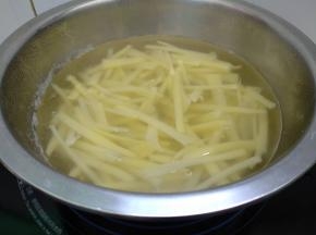锅里水开倒入土豆丝煮熟。